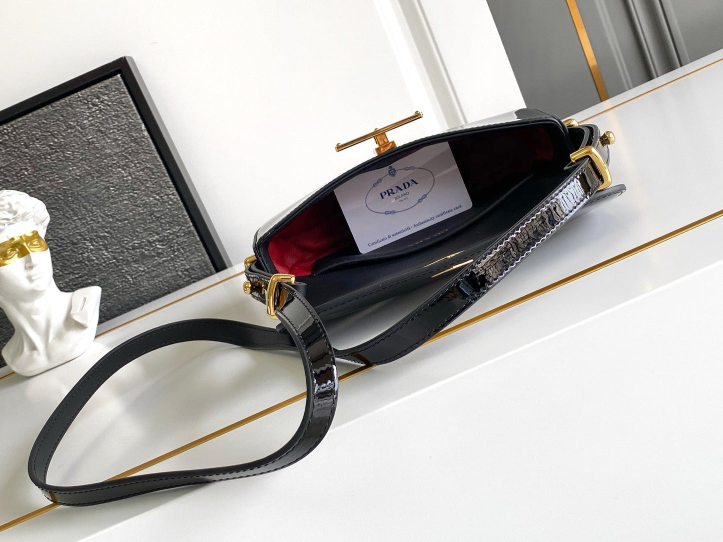 Sac baguette en cuir verni noir avec accents dorés 