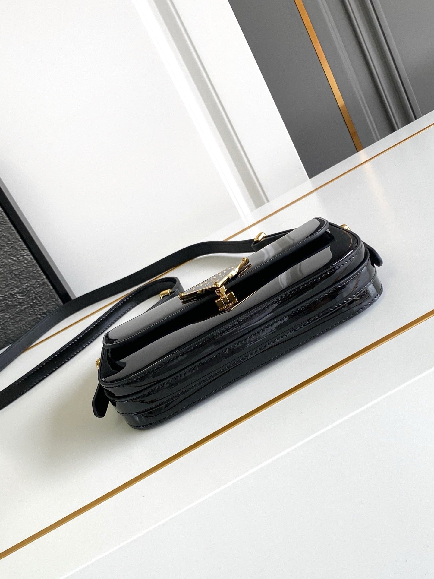 Sac baguette en cuir verni noir avec accents dorés 