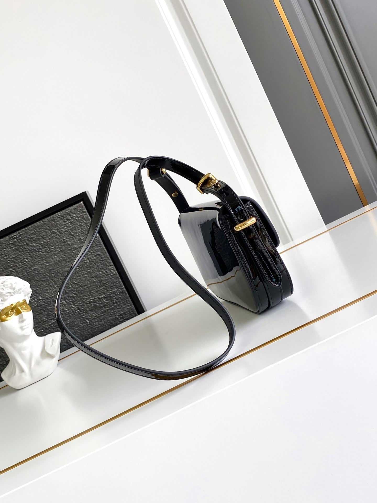 Sac baguette en cuir verni noir avec accents dorés 