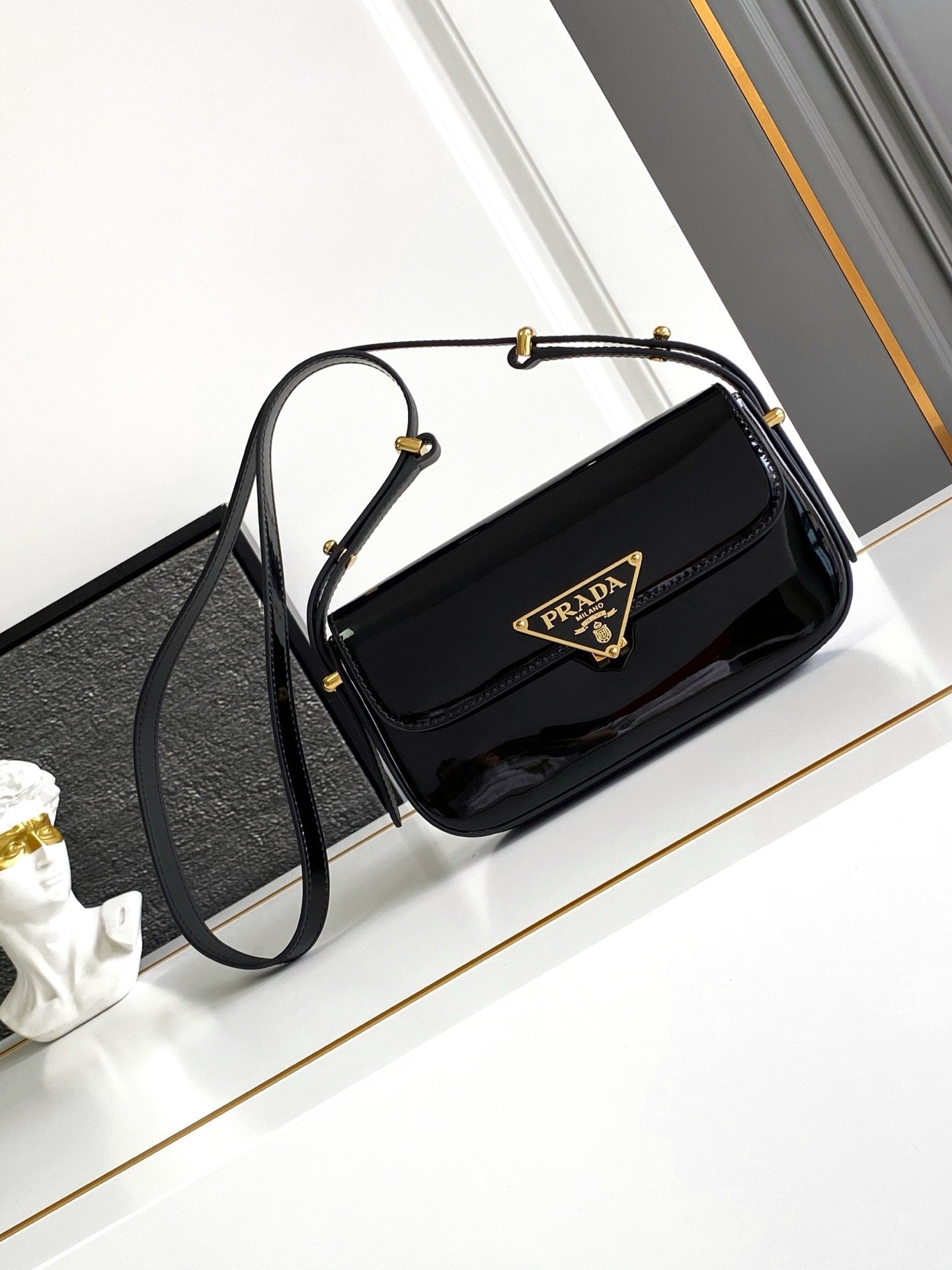 Sac baguette en cuir verni noir avec accents dorés 