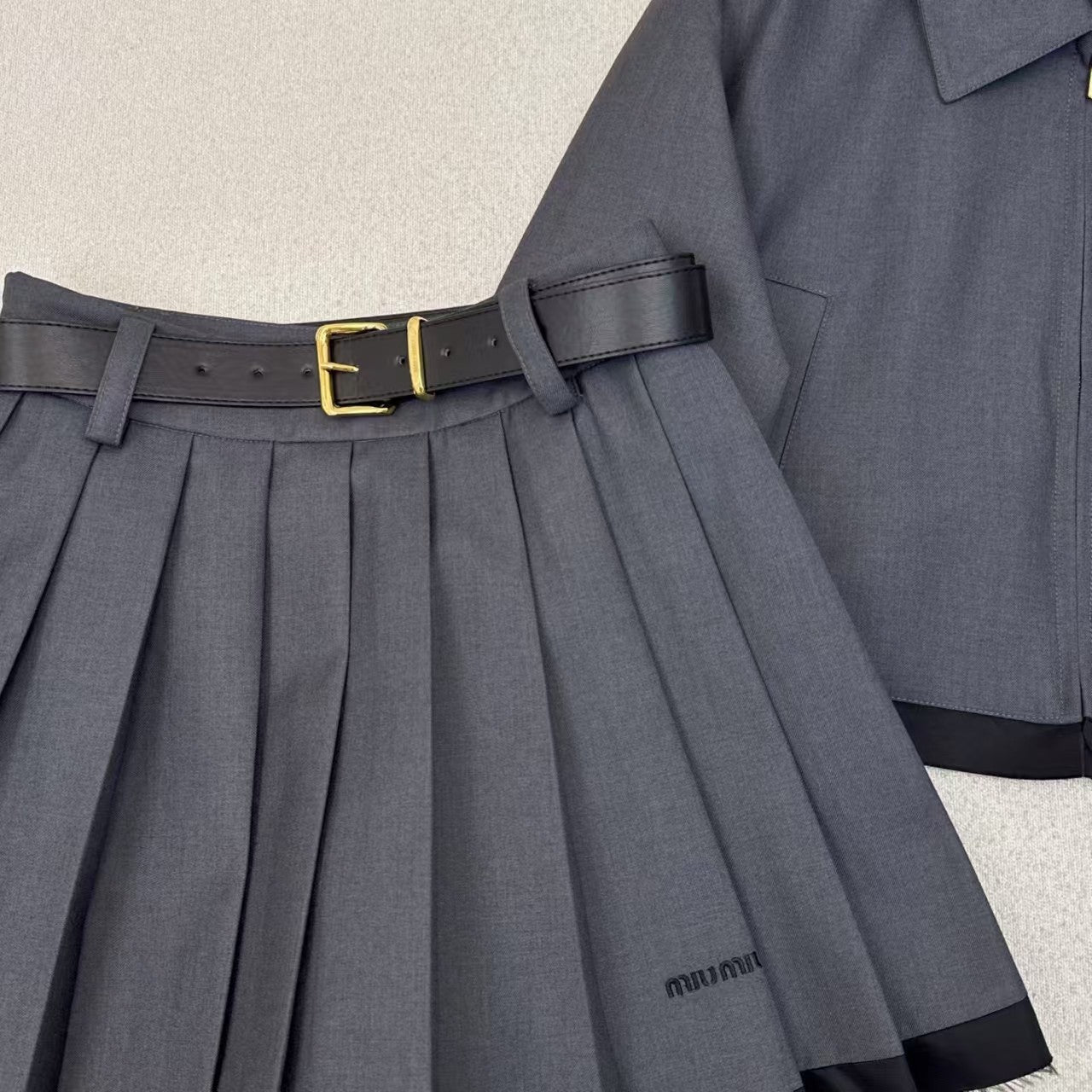 Anzug aus Jacke mit gespleißtem Revers und Faltenrock mit Gürtel