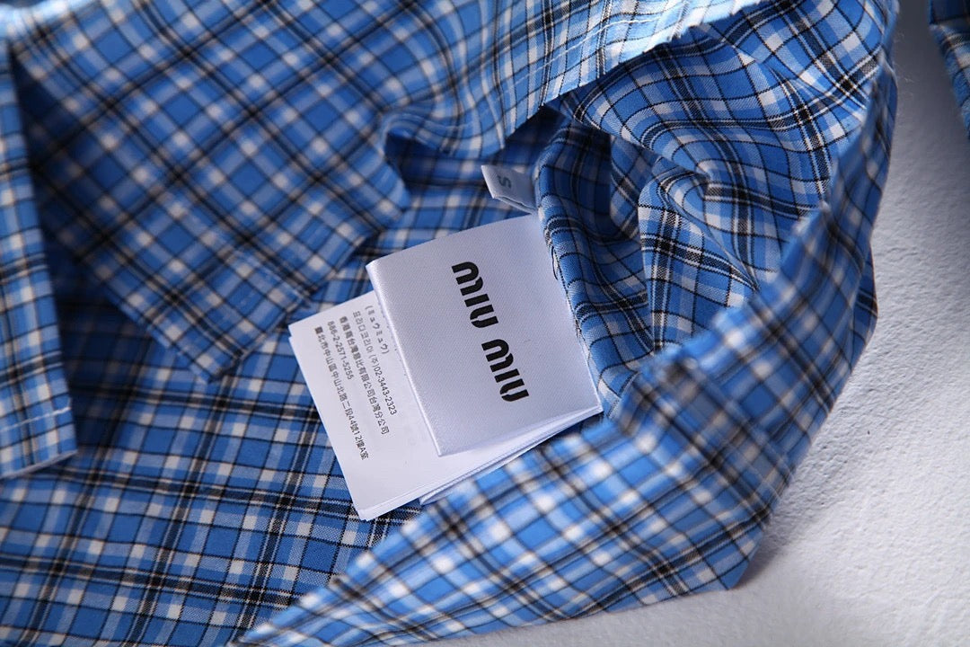 Hellblaues kariertes Hemd mit Pelzbesatz. Hemd mit kleinen karierten Ärmeln und Pelzbesatz. Kariertes Hemd